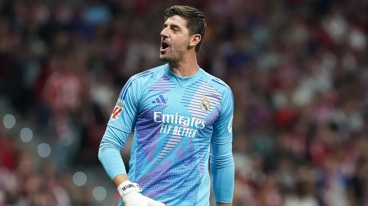 Bramkarz Realu Madryt, Thibaut Courtois, w akcji. Jego błękitny strój z logo Emirates Fly Better i herbem klubu jest dobrze widoczny.