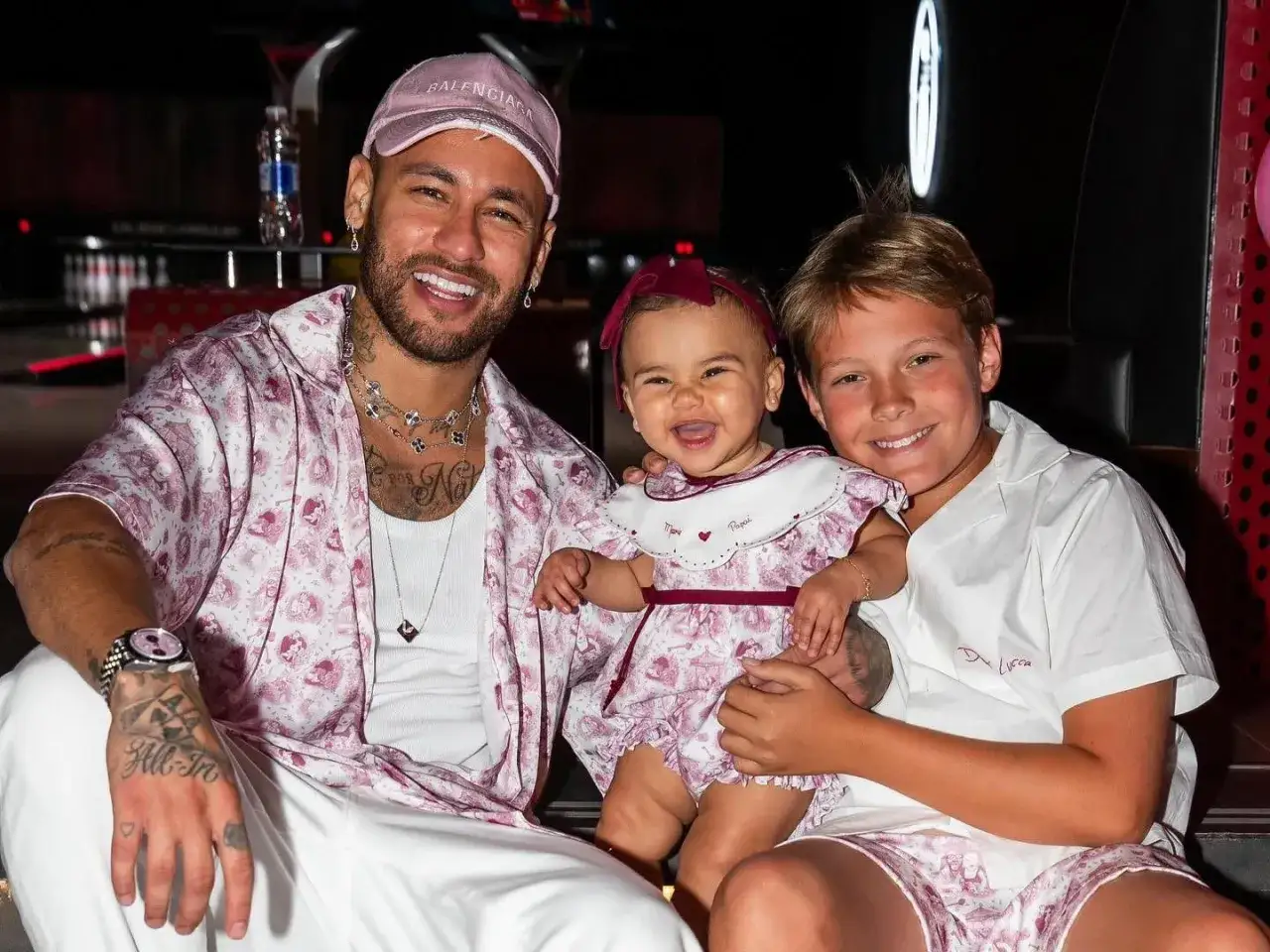 Neymar z uśmiechem pozuje z dwójką swoich dzieci, synem i córką, w dopasowanych strojach.