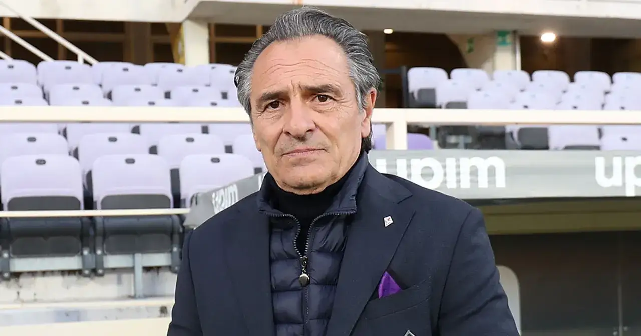 Prandelli, w eleganckim garniturze i kamizelce, stoi na tle pustych trybun stadionu.