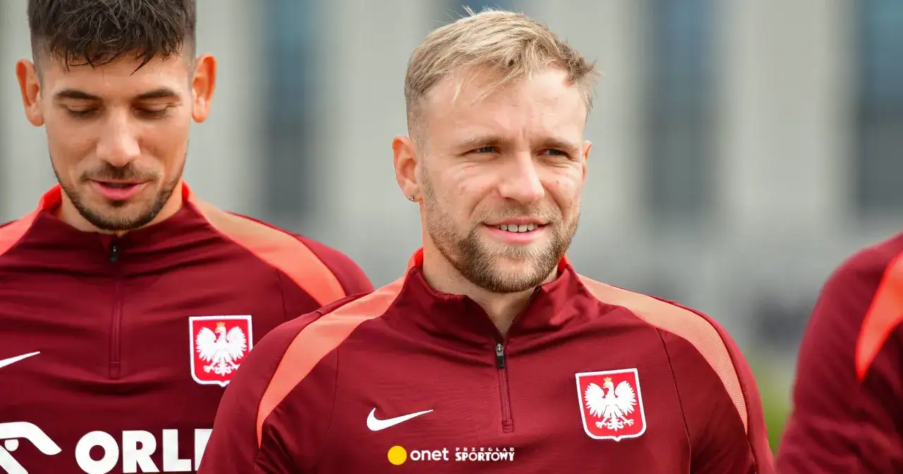 Dwóch piłkarzy w bordowych strojach z orłem. Jeden z nich, z blond włosami, uśmiecha się. To właśnie tam gra puchacz, symbol polskiej drużyny.