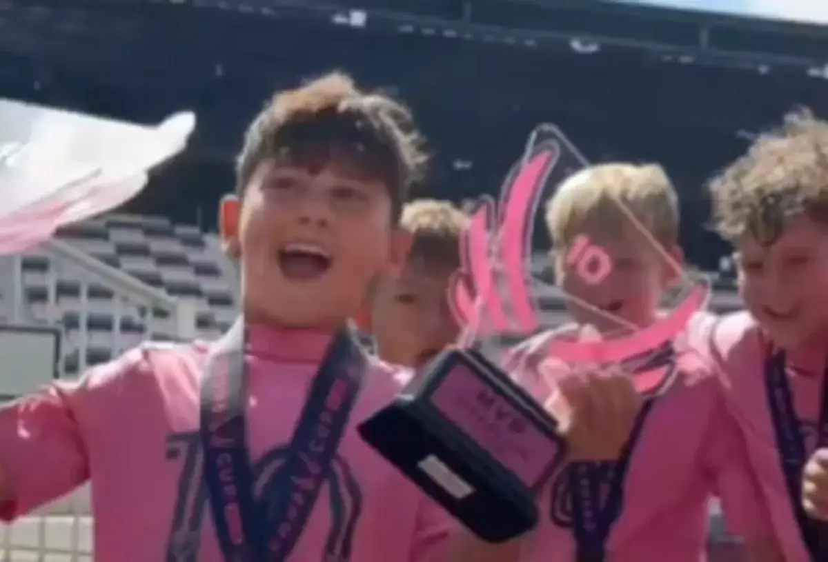 Chłopiec w różowej koszulce, jak młody Thiago Messi, cieszy się ze zwycięstwa z pucharem MVP.