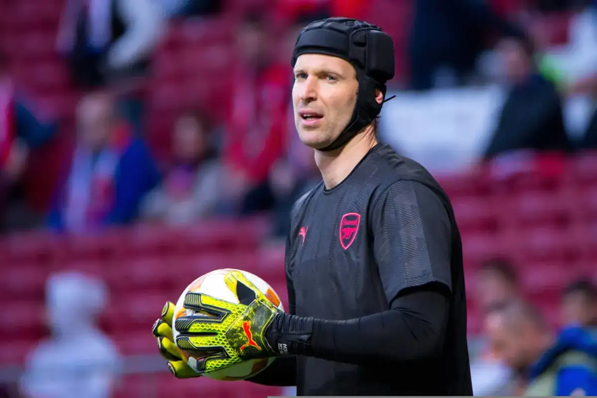 Bramkarz Petr Cech w charakterystycznym kasku, który nosił po kontuzji, trzyma piłkę.
